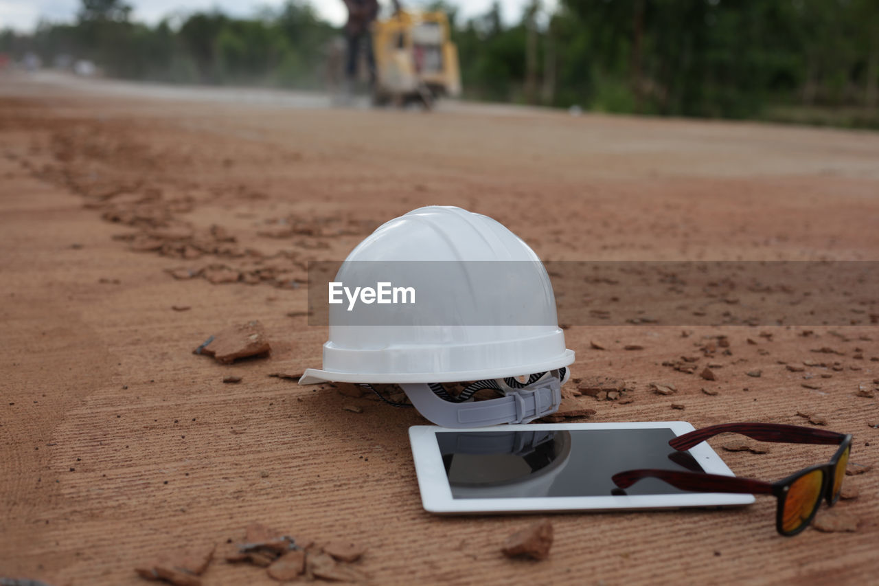 Engineer's helmet, tablet and sunglasses are placed on a concrete road construction site.