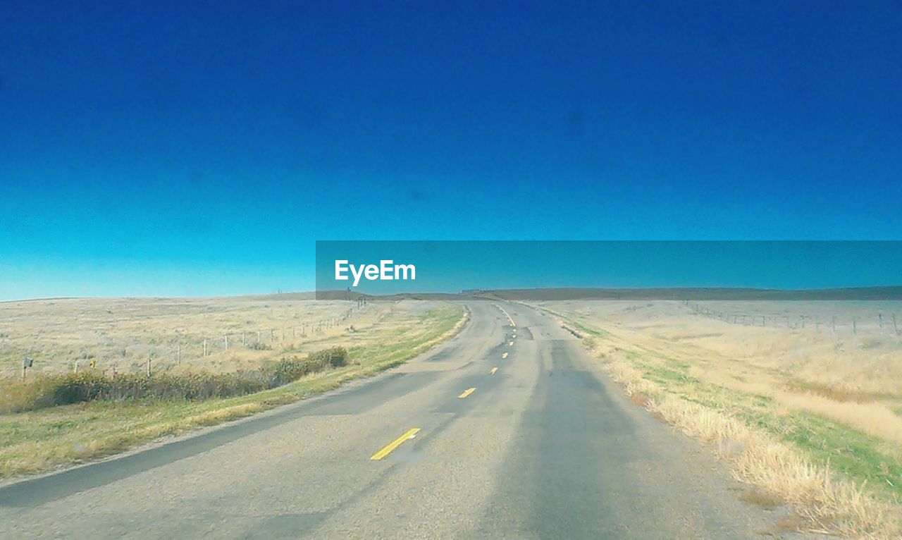 EMPTY COUNTRY ROAD ALONG LANDSCAPE AGAINST BLUE SKY