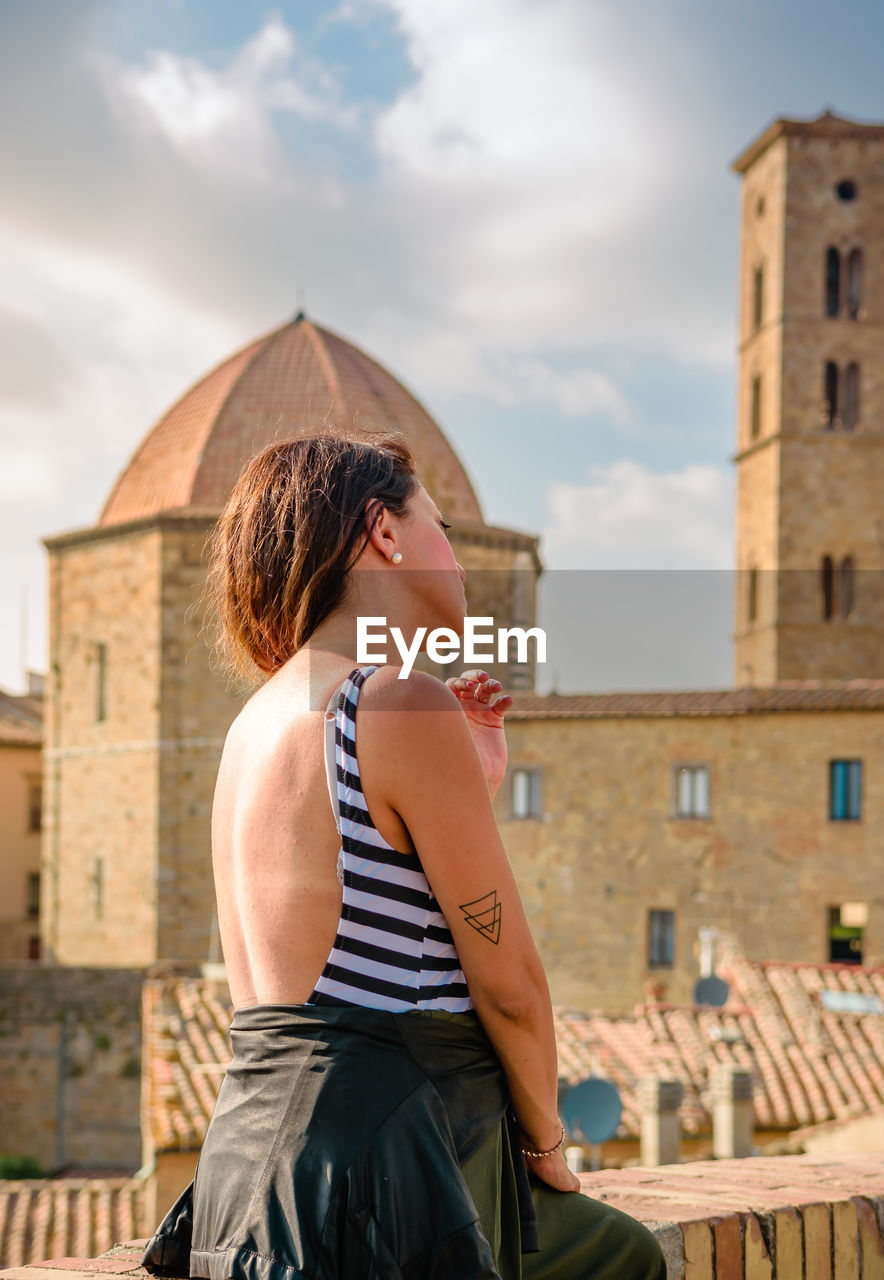 Woman sitting against buildings in city