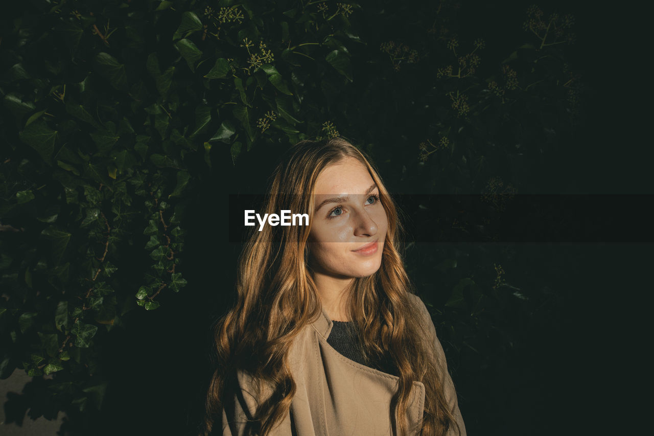 Beautiful young woman standing against plants