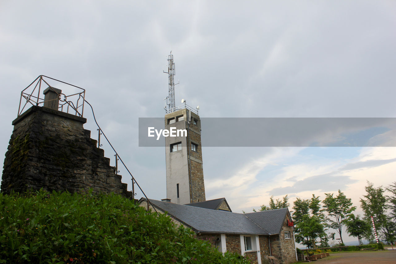 LOW ANGLE VIEW OF CROSS BY BUILDINGS AGAINST SKY