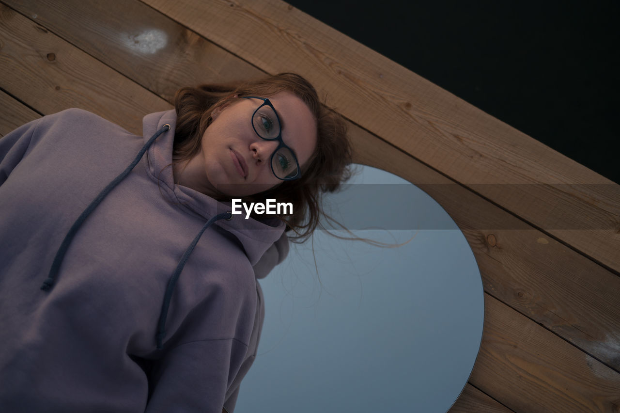 high angle view of young woman sitting on wooden wall