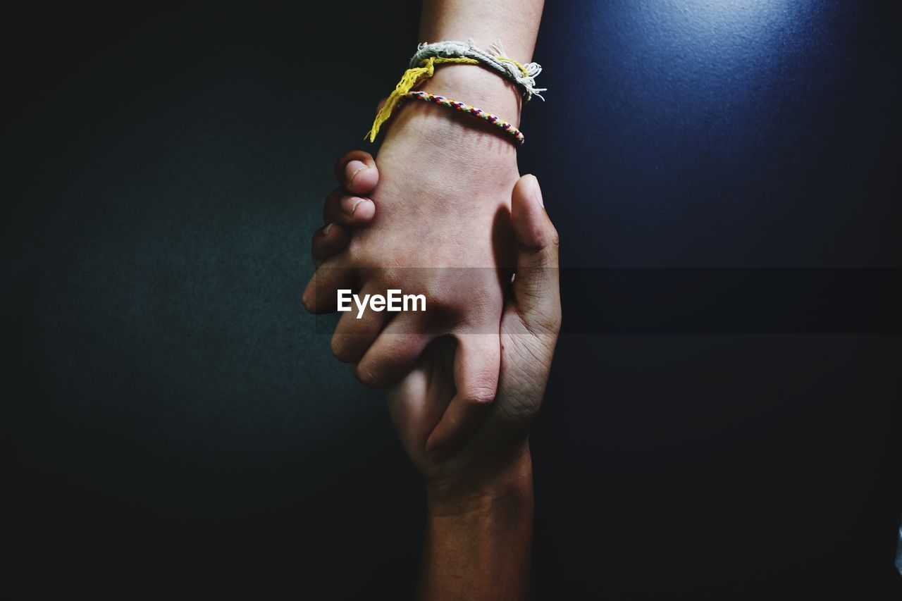 CLOSE-UP OF WOMAN HAND AGAINST BLACK BACKGROUND