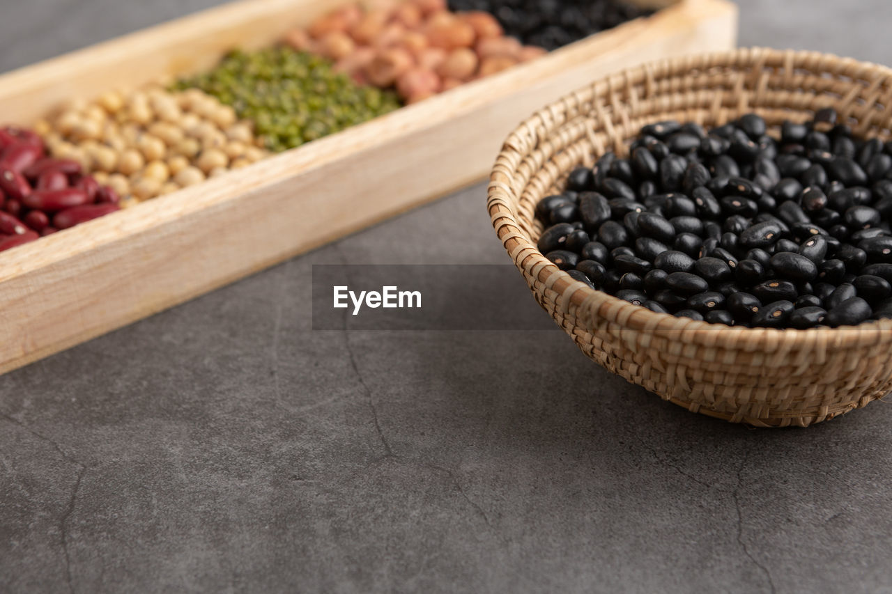 Black beans and grains in the wooden basket and in the wooden tray on the table. high angle view.
