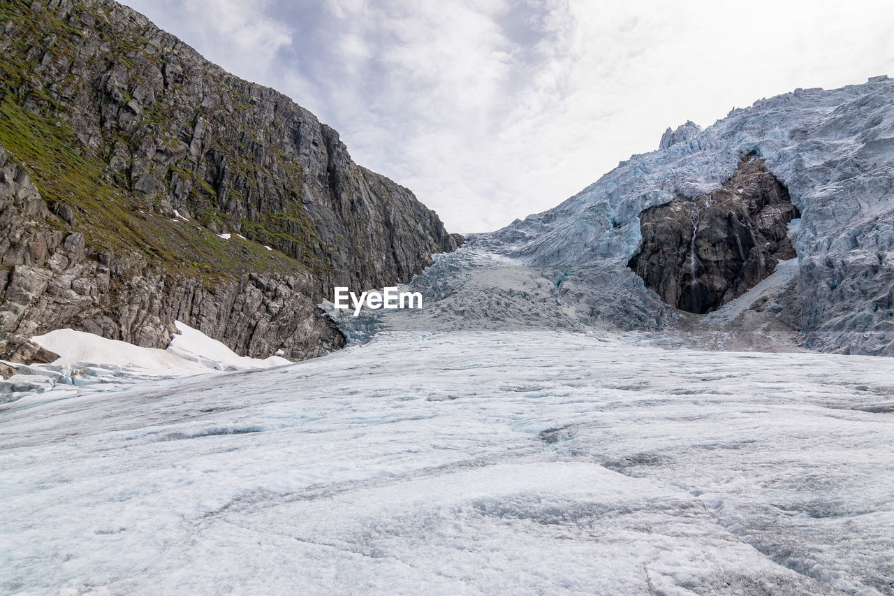 Low angle view of snow covered mountain against cloudy sky