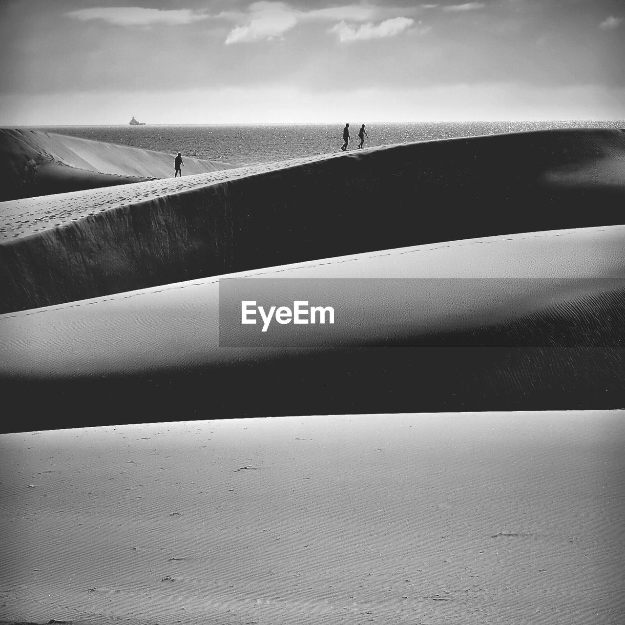 Mid distance of people walking on sand dune by sea at maspalomas