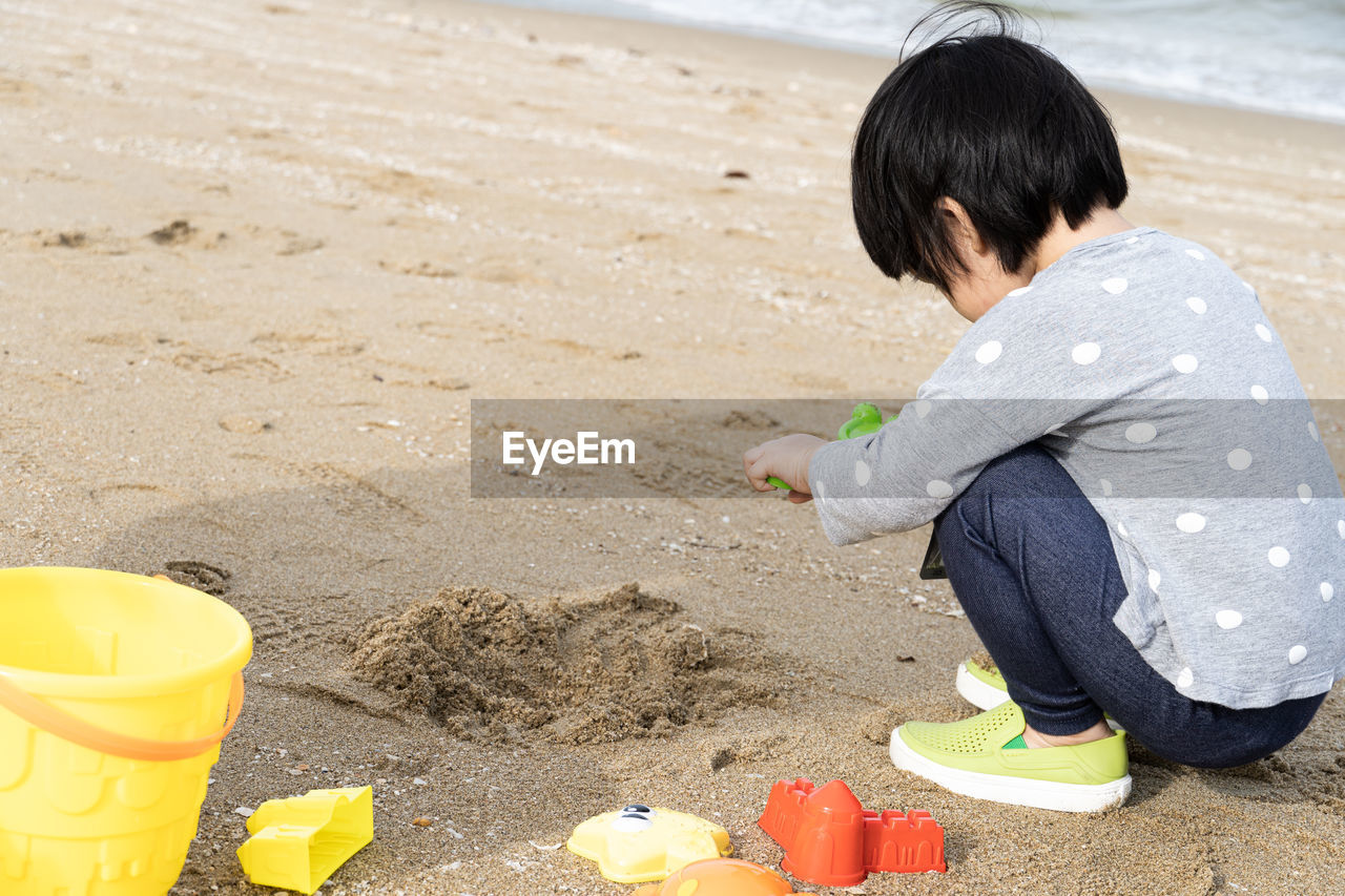 3 years old asian kid play sand on the beach. background for family life and education