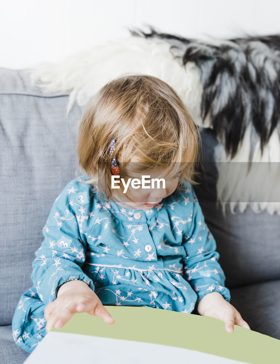 Cute girl holding paper sitting on sofa at home