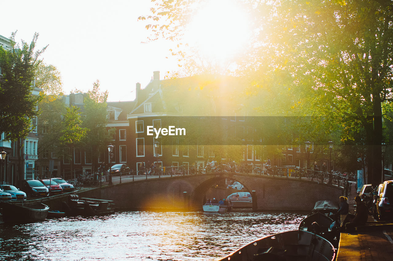 Footbridge over river in city during sunset