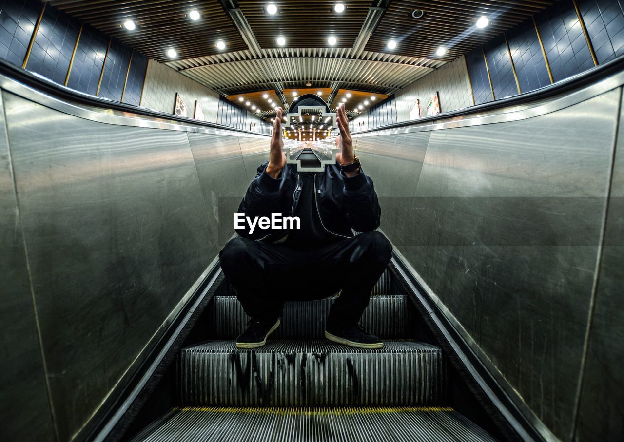 Headless man sitting on escalator