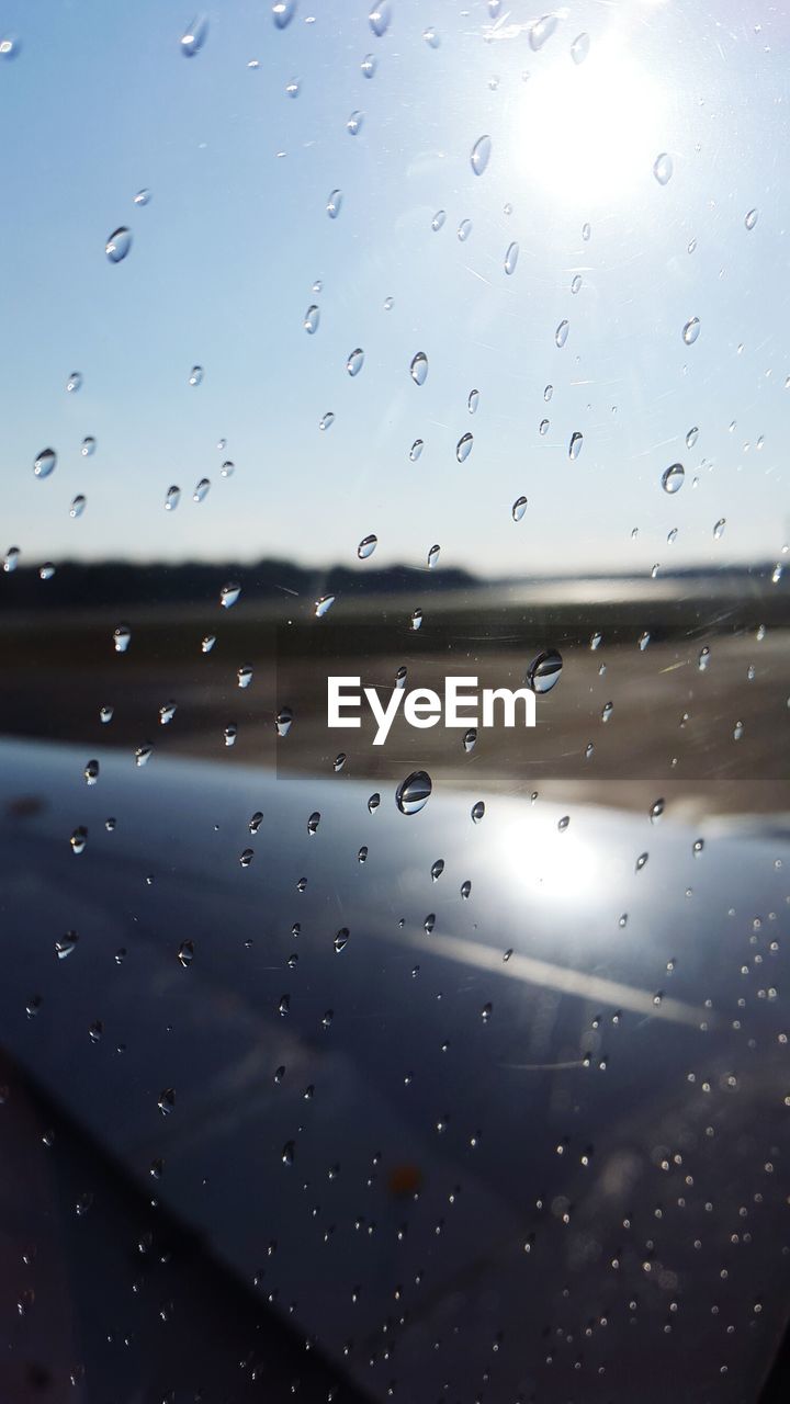 FULL FRAME SHOT OF RAINDROPS ON WINDOW AGAINST SKY