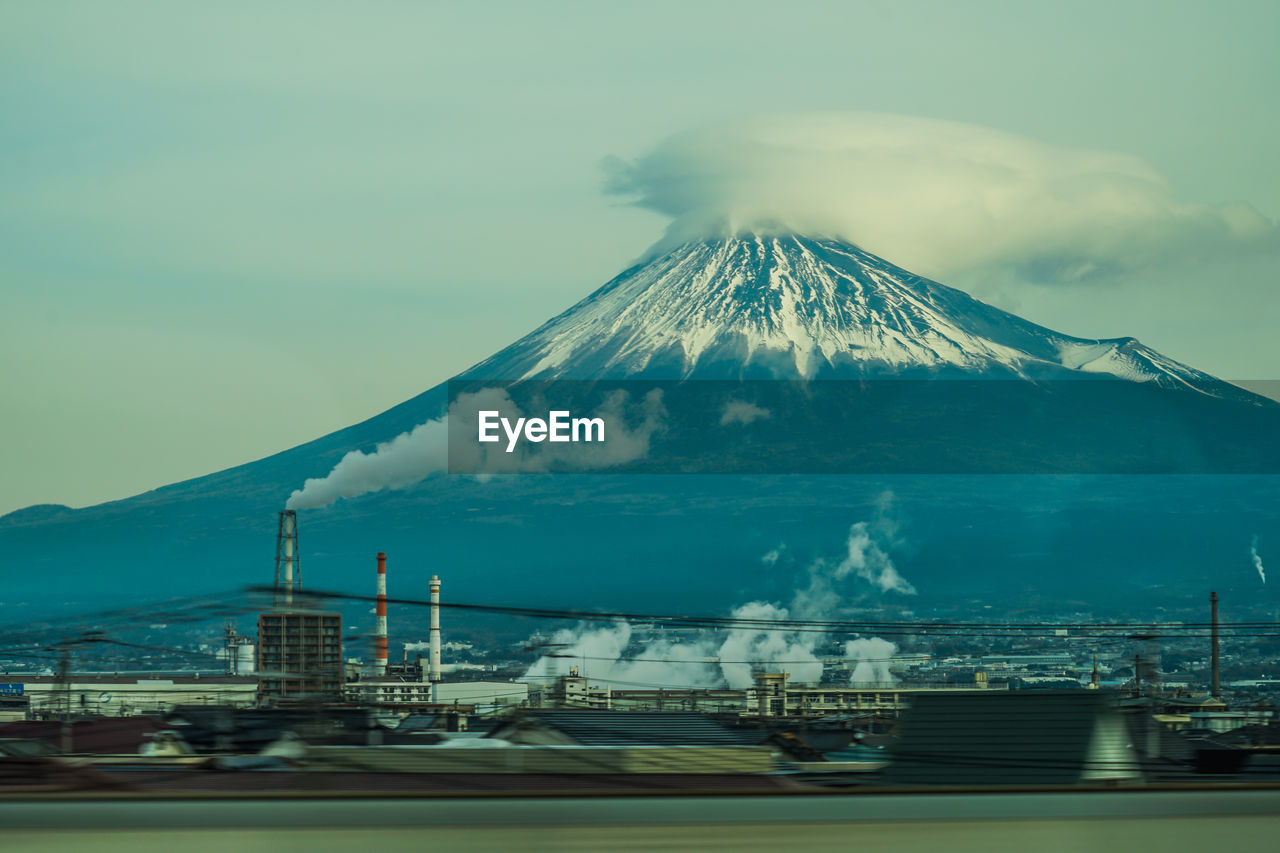 mountain, volcano, sky, nature, beauty in nature, no people, travel destinations, horizon, transportation, architecture, snow, stratovolcano, landscape, smoke, scenics - nature, environment, cold temperature, cloud, water, winter, outdoors, travel, sea, snowcapped mountain, built structure, land, building exterior, city, mode of transportation