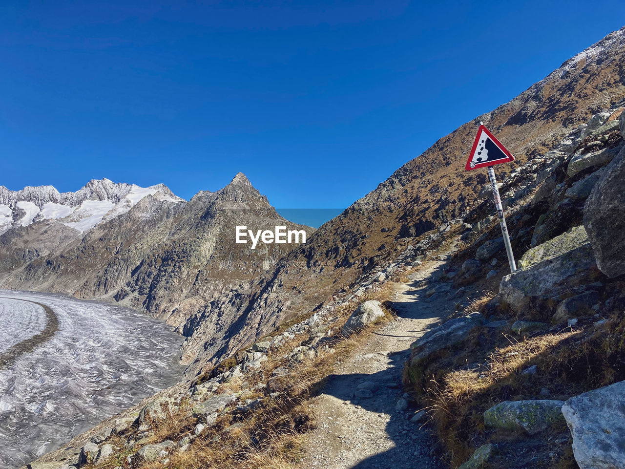 mountain, mountain range, scenics - nature, sky, environment, nature, ridge, landscape, flag, adventure, beauty in nature, mountain pass, blue, rock, walking, wilderness, day, clear sky, summit, travel destinations, snow, travel, tranquility, outdoors, tranquil scene, land, no people, mountaineering, sunny, non-urban scene, backpacking, sunlight, geology, activity, patriotism, leisure activity, plateau, cold temperature, moraine, cirque, extreme terrain, winter, terrain, valley, sports