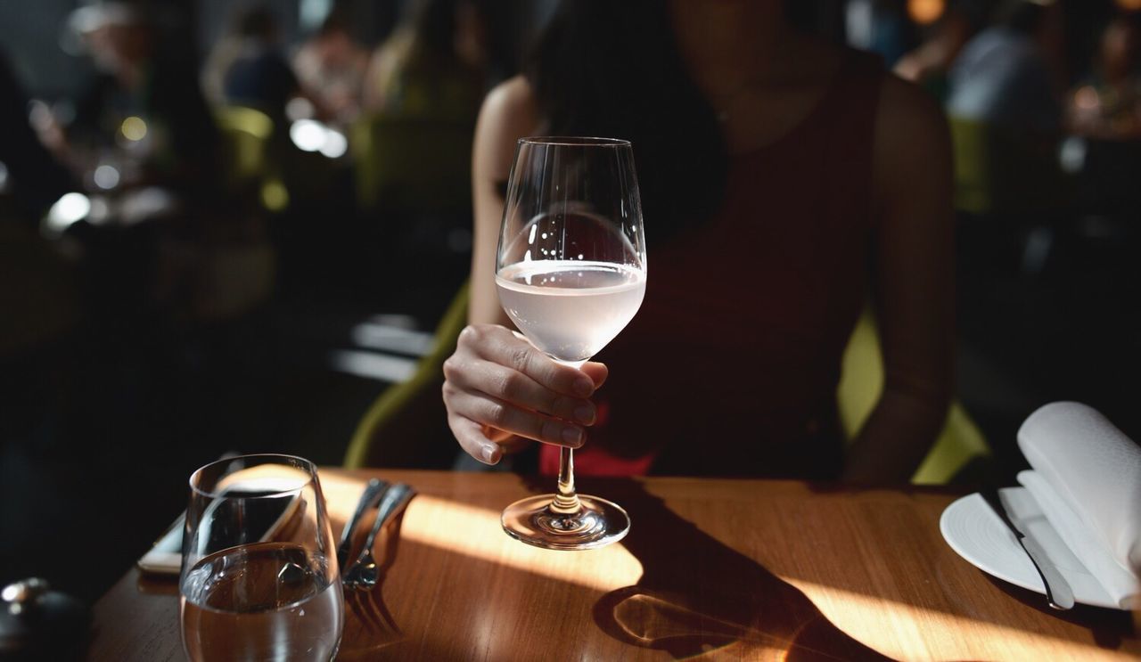 Midsection of woman holding drinking glass at restaurant