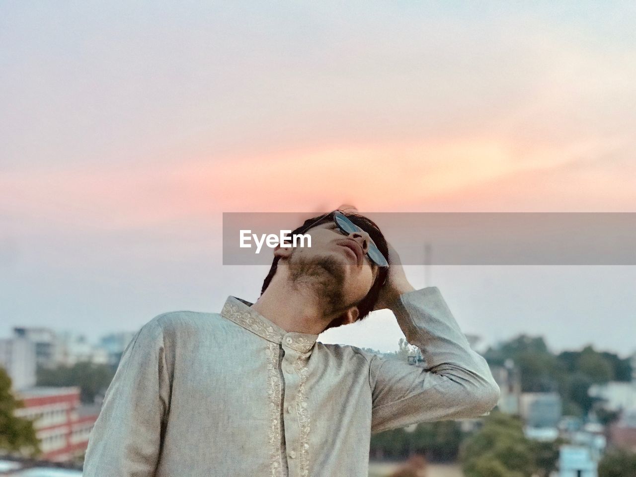 Teenage boy looking up against sky during sunset