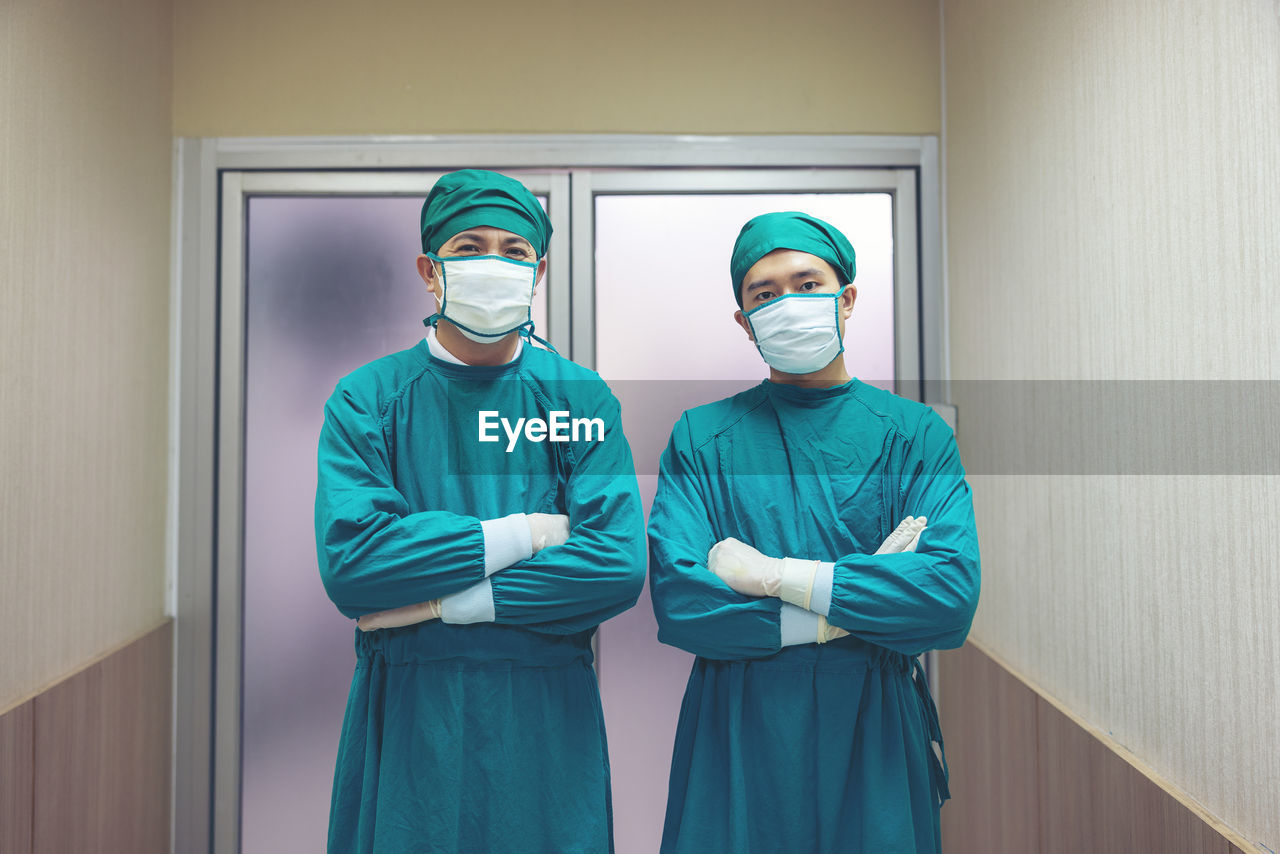 Portrait of a male surgeon in an operating room with a team of doctors in the background.