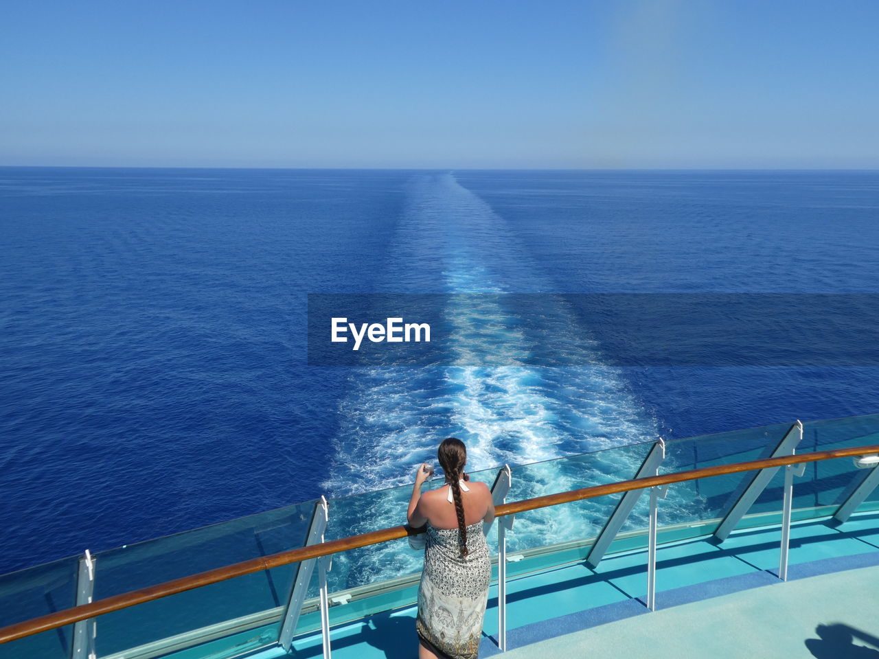 Rear view of woman standing by railing in boat on sea