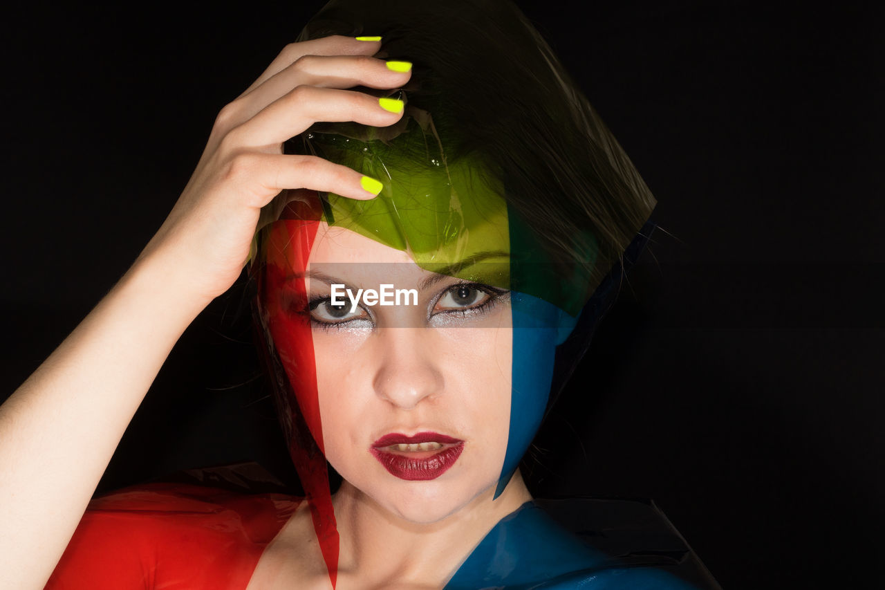 Portrait of fashion model with colorful plastic against black background