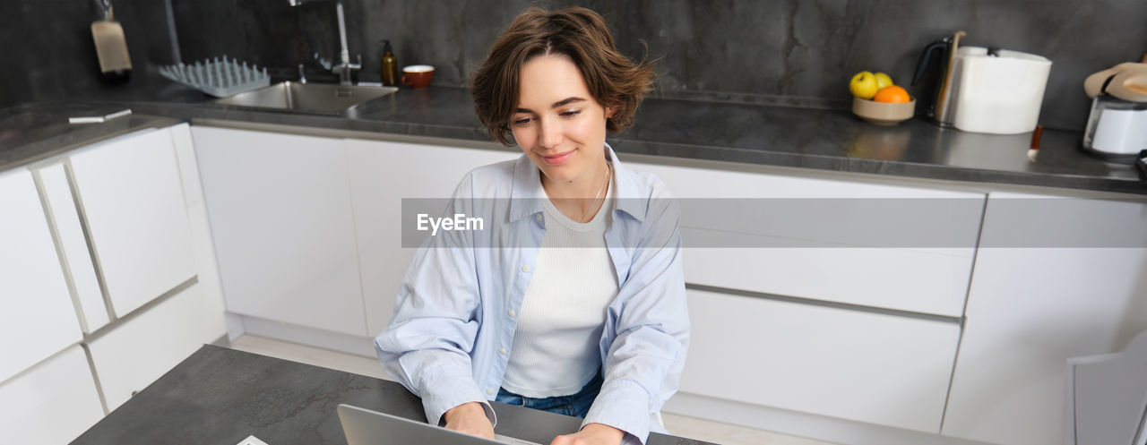 portrait of young woman sitting in kitchen