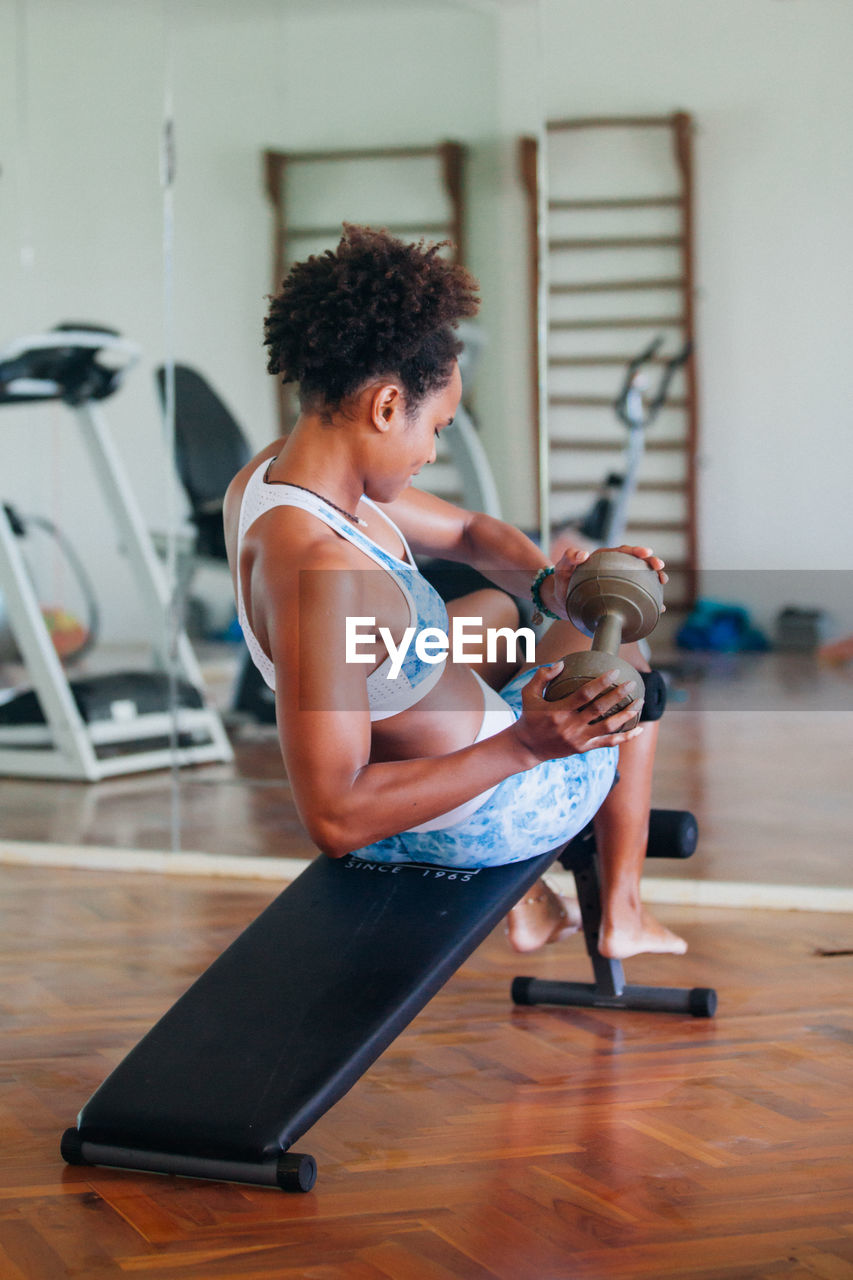 Young woman lifting dumbbell at gym