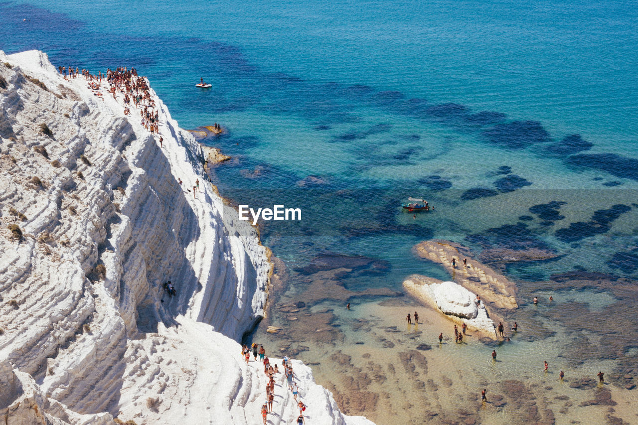 High angle view of people on cliff by sea