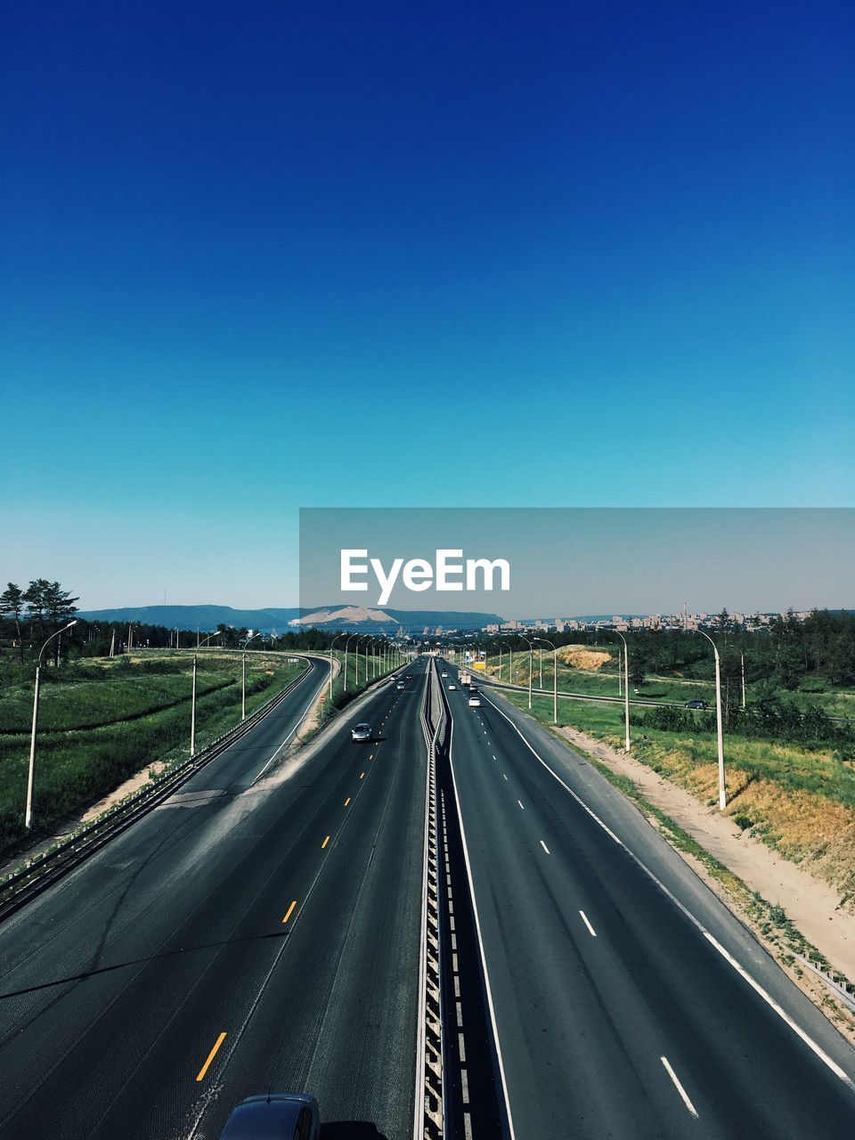Highway amidst landscape against clear blue sky