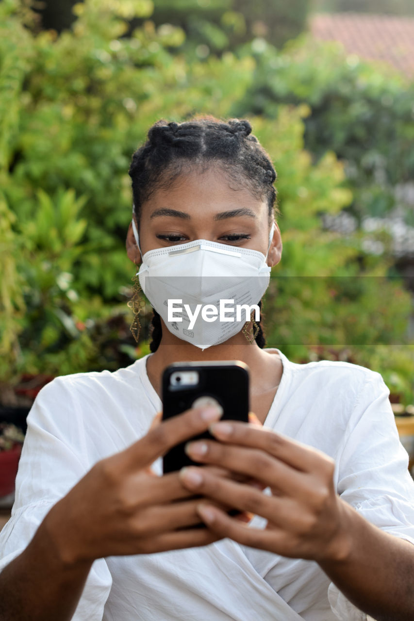 Young black woman in face mask using a smartphone