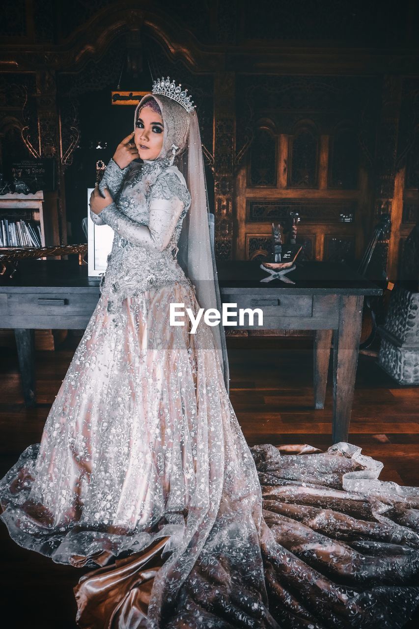 Portrait of bride wearing traditional clothing standing indoors