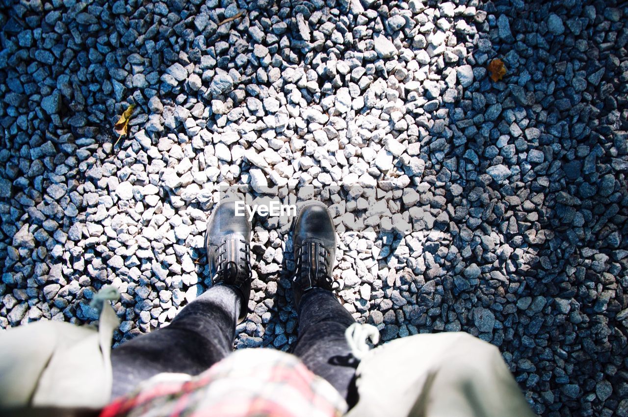 Low section of woman standing on stones at field