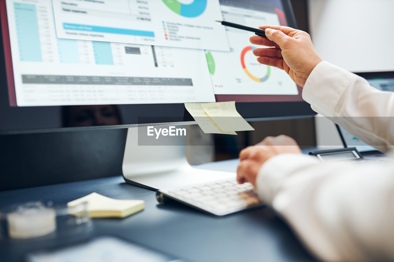 Woman entrepreneur working with financial and sale data on charts and graphs on computer screen