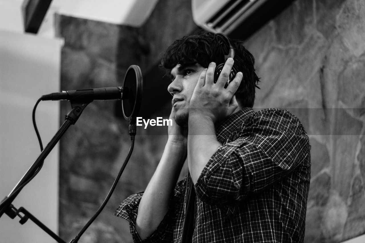 Low angle view of mid adult man singing in recording studio