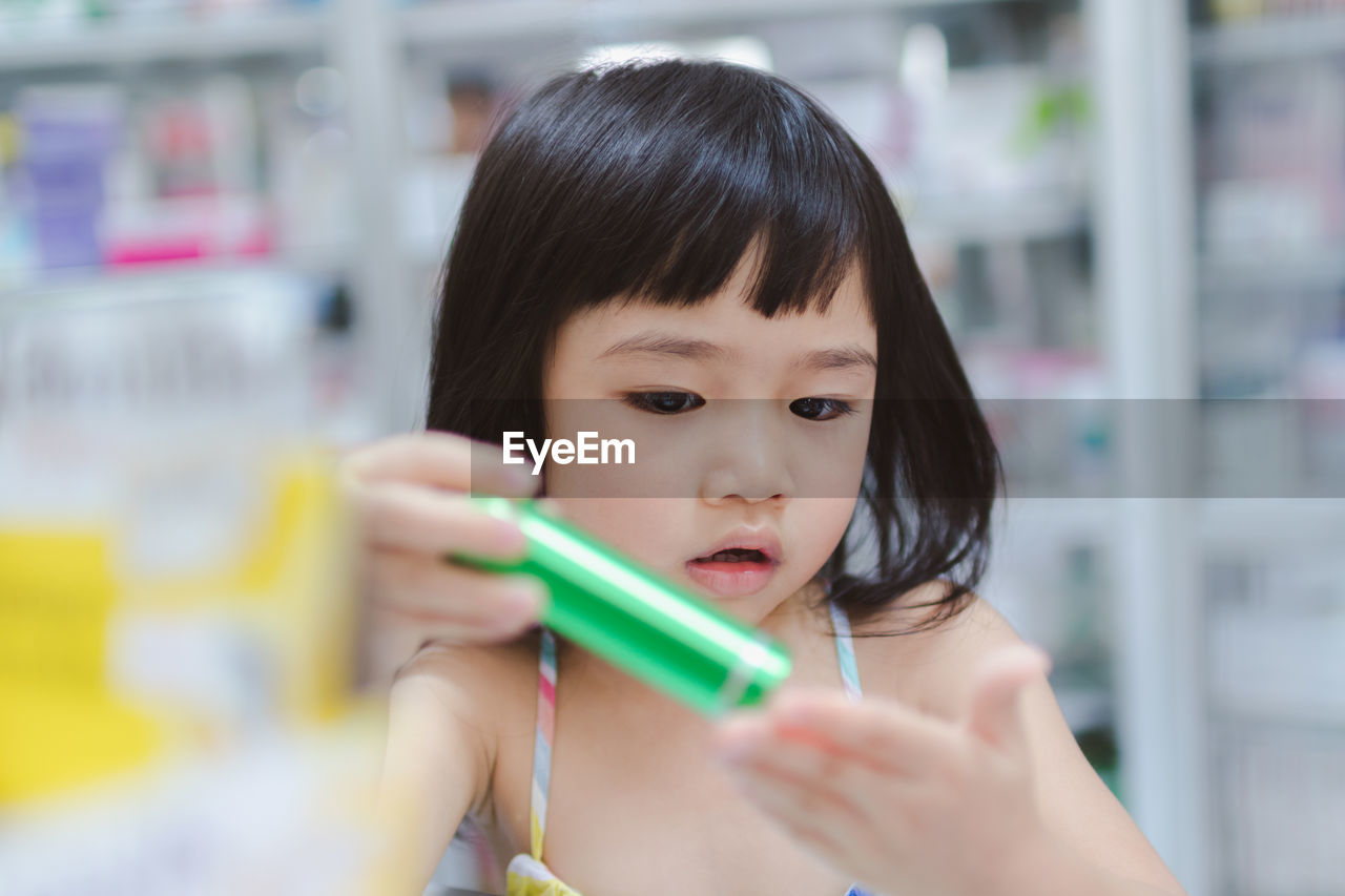 Close-up of girl holding flashlight at home