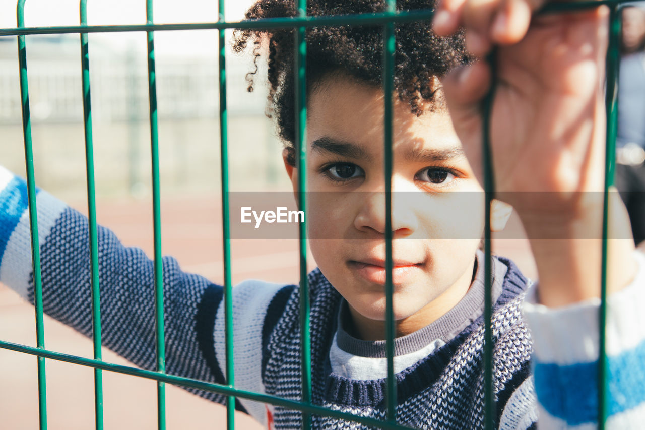 Portrait of cute boy seen through fence