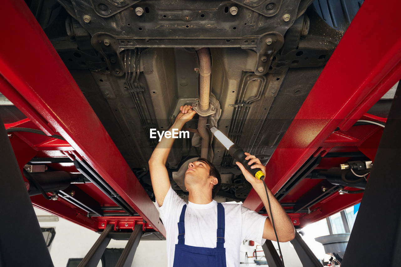 Low angle view of mechanic repairing car in garage