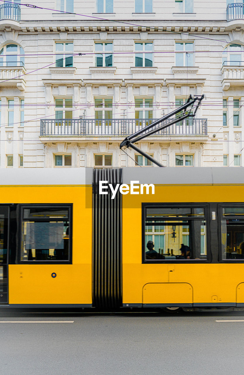 YELLOW TRAIN ON STREET AGAINST BUILDINGS