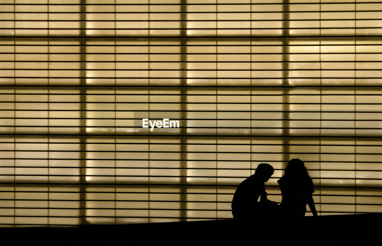 SILHOUETTE COUPLE KISSING AGAINST BLURRED WALL