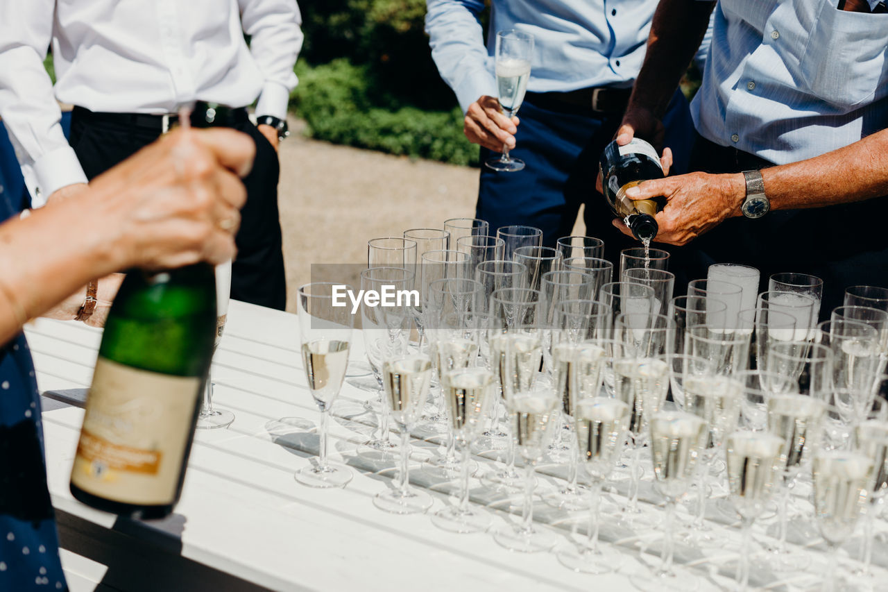 Midsection of men standing by champagne at wedding ceremony