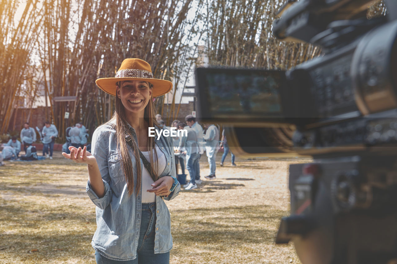 Exterior shot of young beautiful woman vlogging, happy smiling young vlogger possing on the camera.