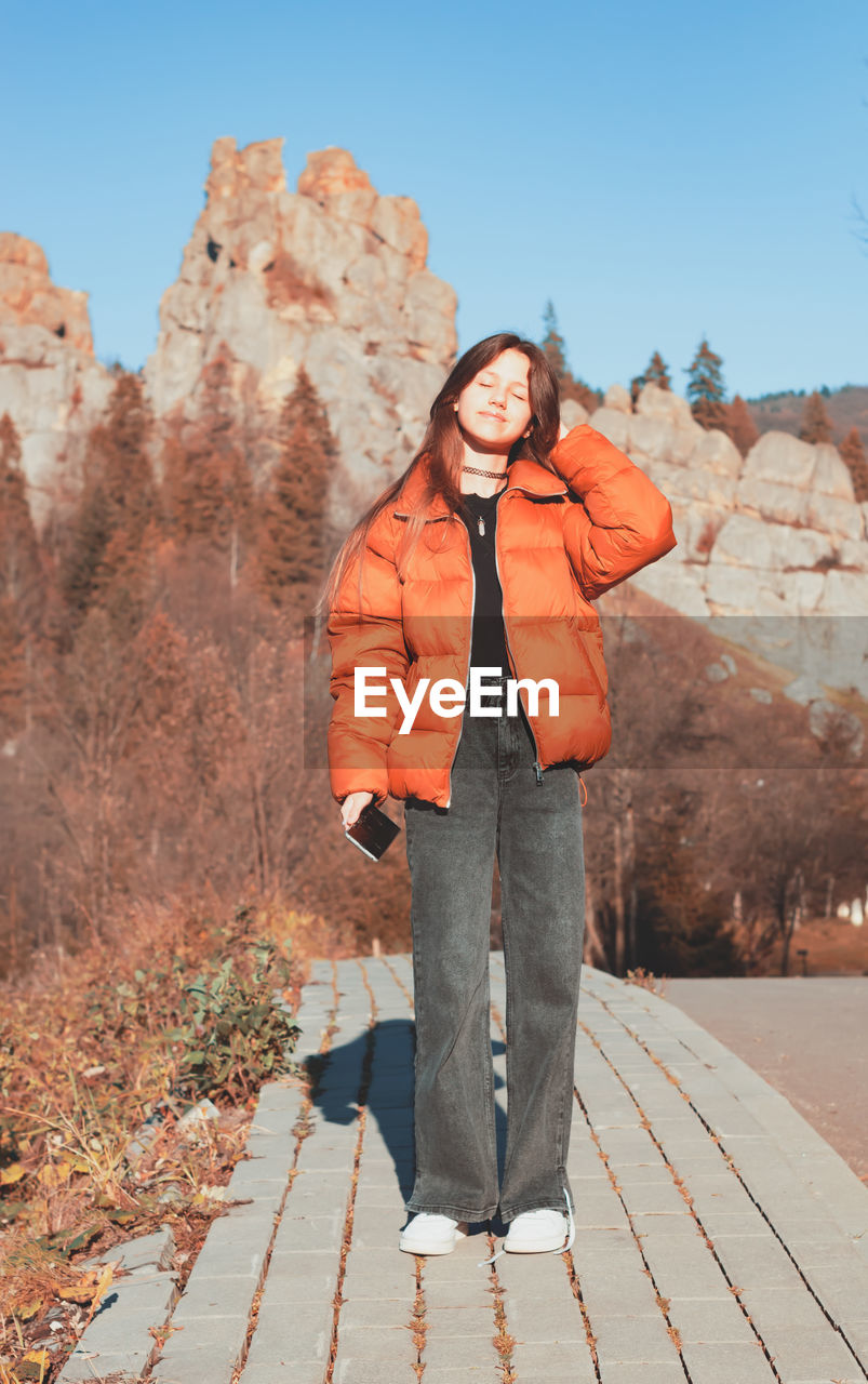 Portrait of a girl in a jacket on a mountain background.