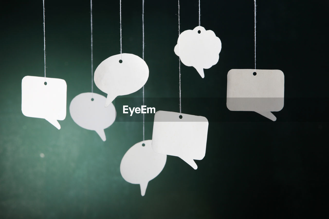 Close-up of speech bubbles hanging against wall