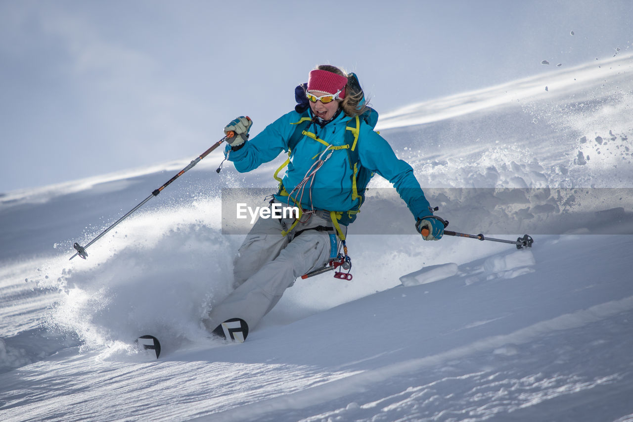 Young woman skiing on snowfield against sky