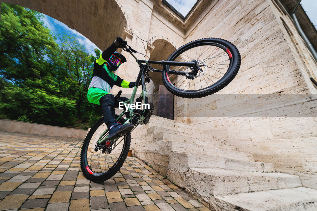 Active young biker jumping on the rear wheel of a mountain bike. extreme sport. wide angle front