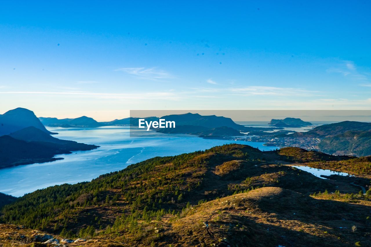 Scenic view of sea and mountains against blue sky