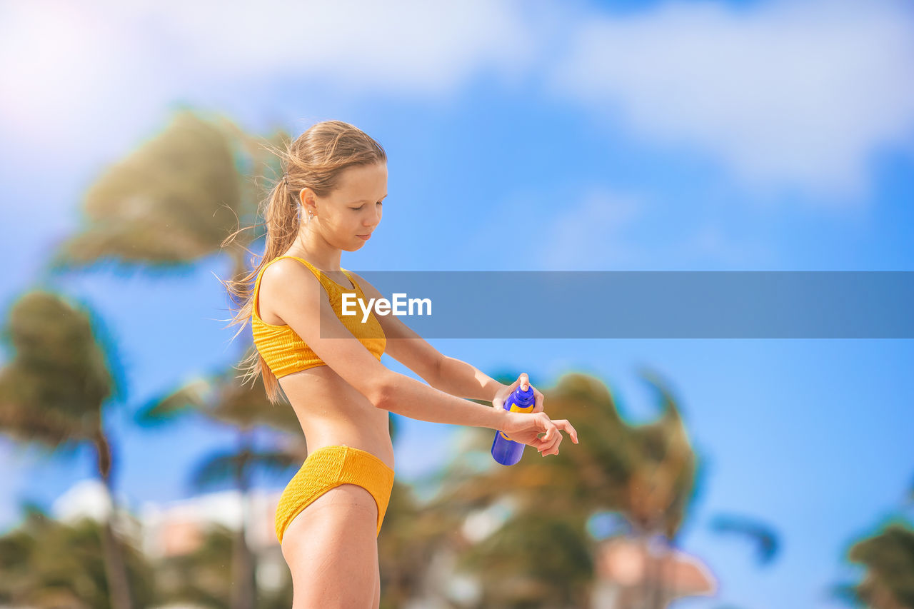 low angle view of young woman doing yoga against sky