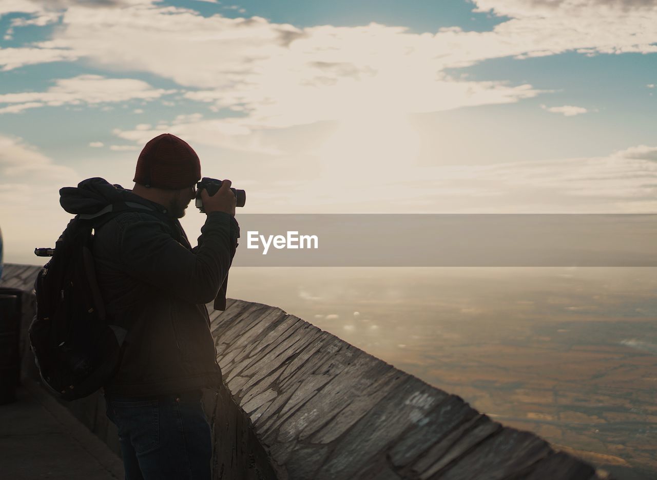 Rear view of man photographing at camera