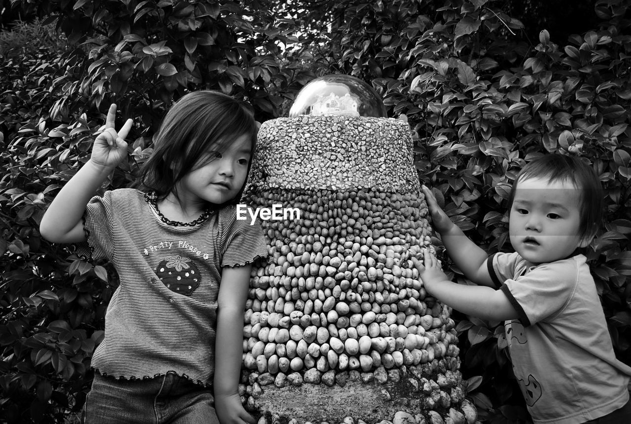 Siblings standing by stone decoration at park