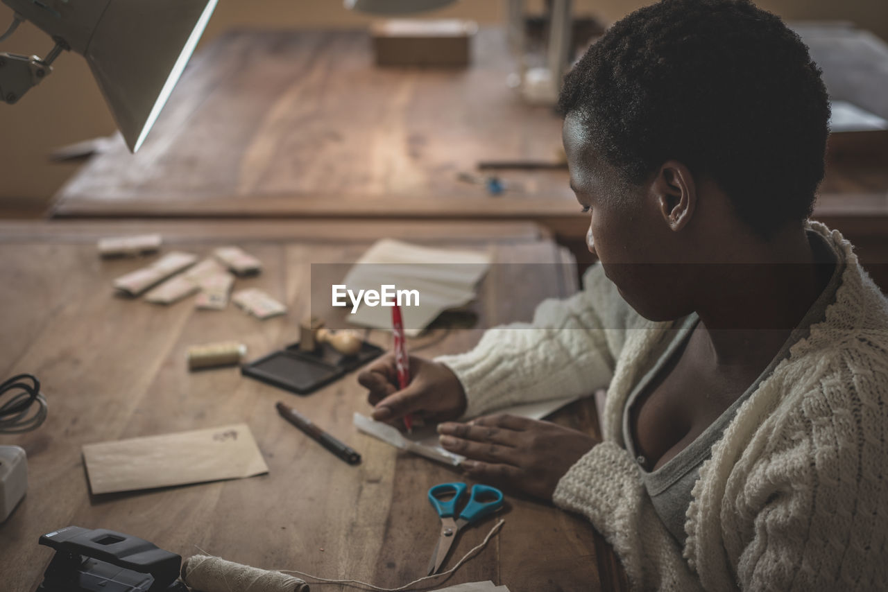 Side view of young african woman working in workshop