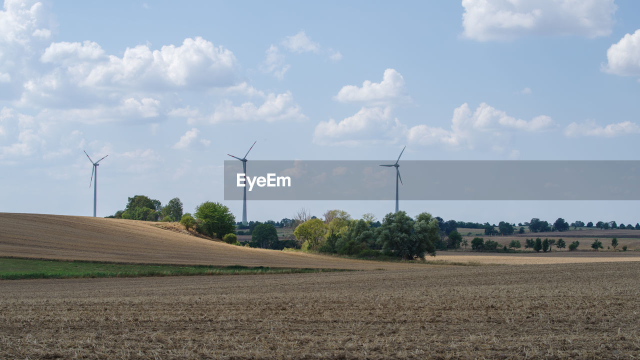 WIND TURBINES ON FIELD AGAINST SKY