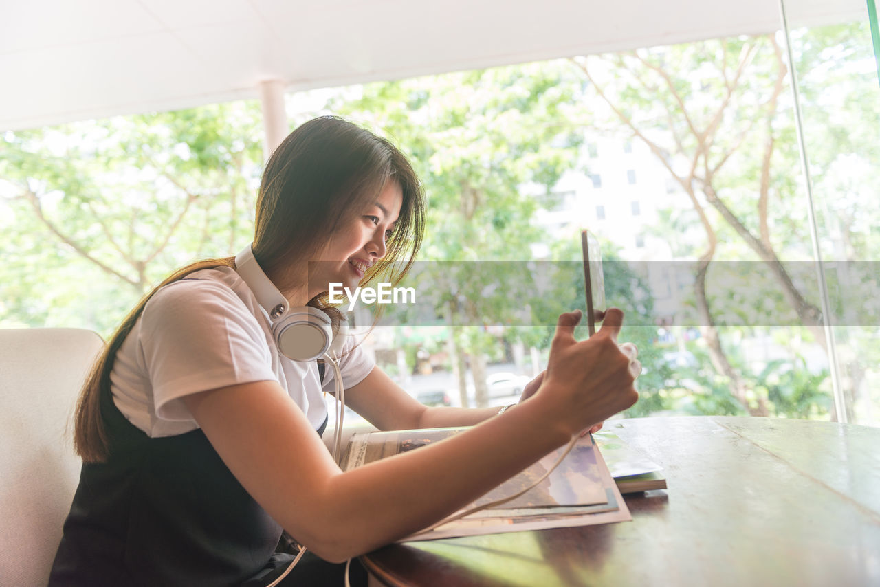 young woman using mobile phone while sitting at home