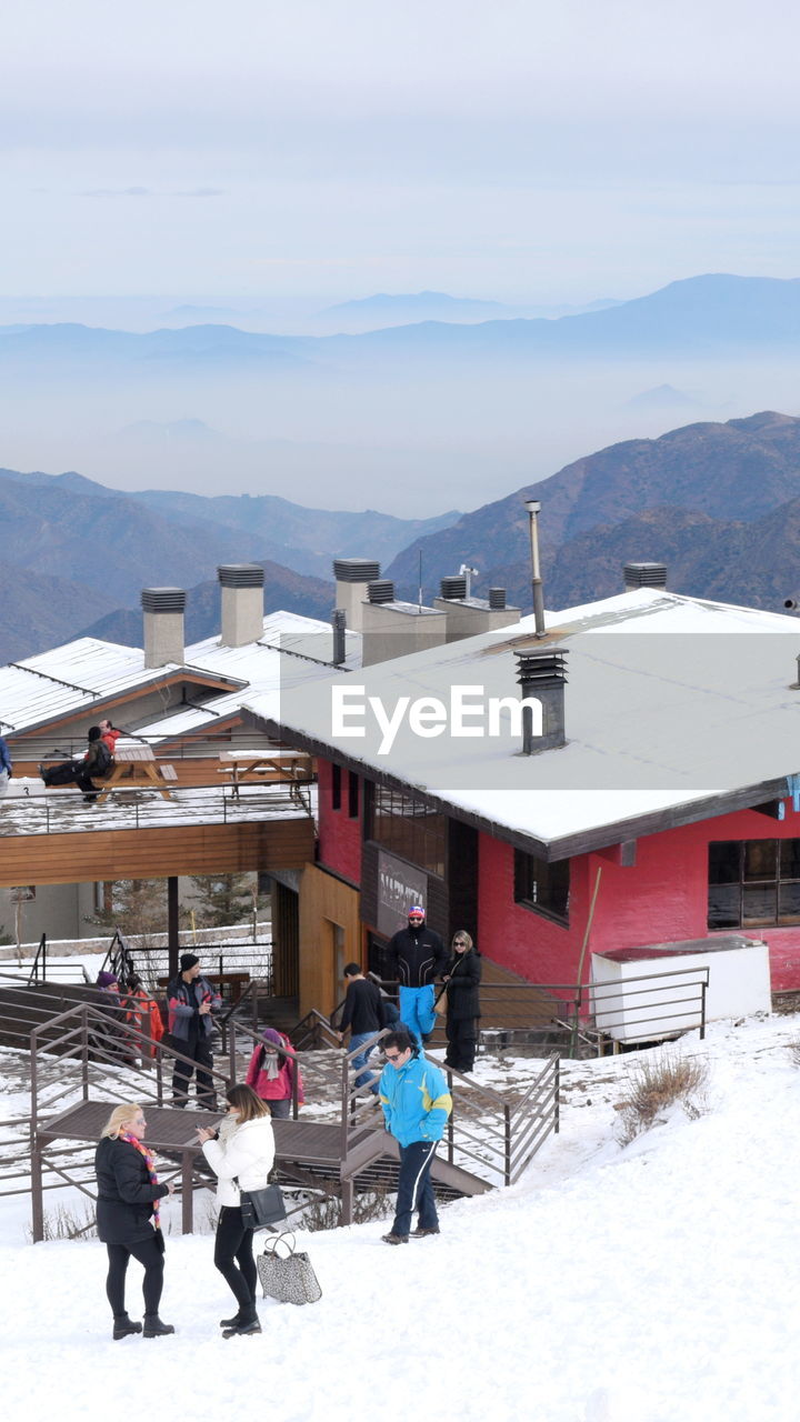 VIEW OF PEOPLE ON SNOW COVERED MOUNTAIN AGAINST SKY